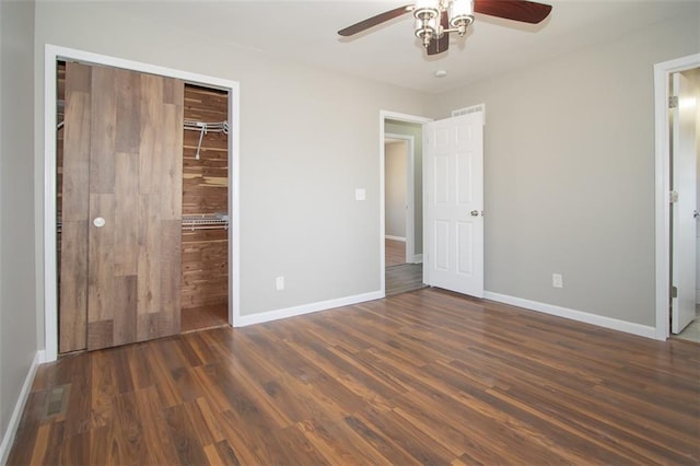 unfurnished bedroom featuring ensuite bath, wood finished floors, a closet, baseboards, and ceiling fan