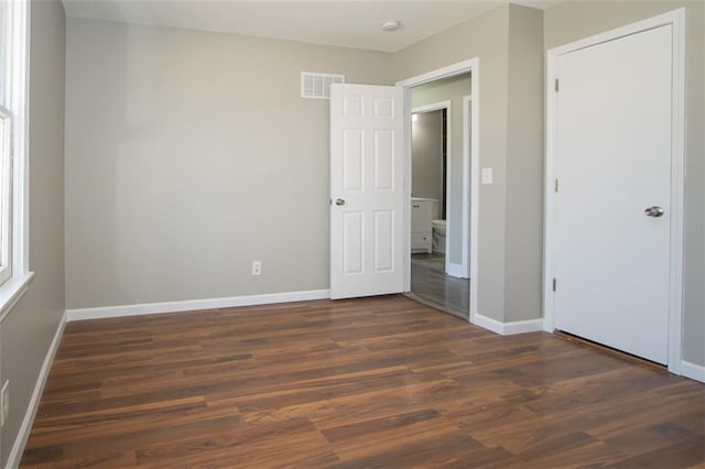 unfurnished bedroom with dark wood-type flooring, baseboards, and visible vents