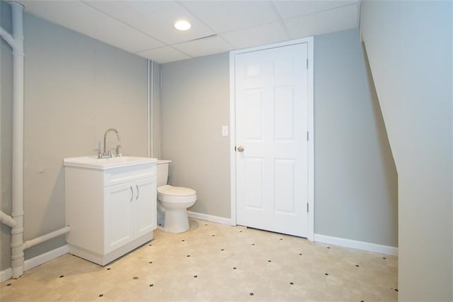 bathroom with baseboards, toilet, tile patterned floors, vanity, and a paneled ceiling