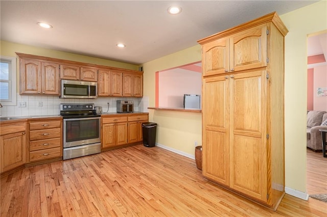 kitchen featuring backsplash, appliances with stainless steel finishes, and light wood-style flooring