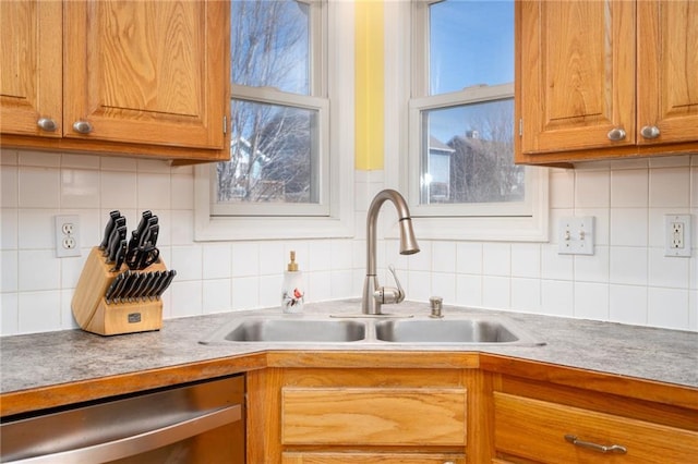 kitchen featuring dishwasher, brown cabinets, backsplash, and a sink