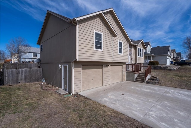 view of home's exterior featuring a residential view, an attached garage, driveway, and fence