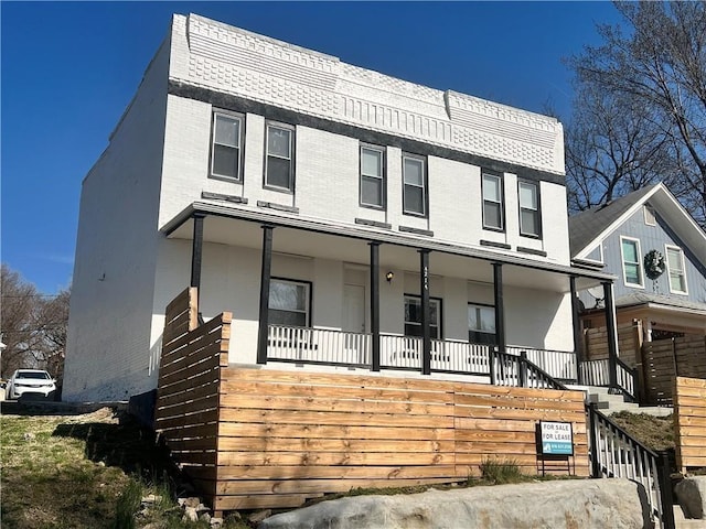 view of front of house with stairway, brick siding, and covered porch