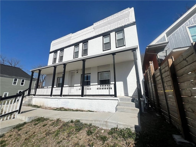 view of front of home featuring covered porch and fence