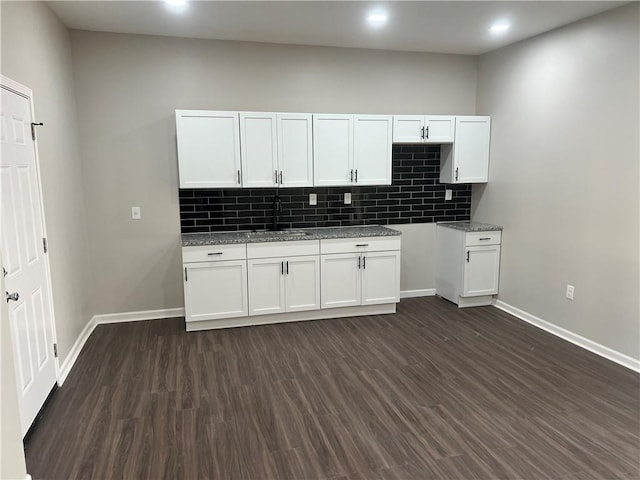 kitchen with white cabinetry, dark wood-type flooring, tasteful backsplash, and a sink