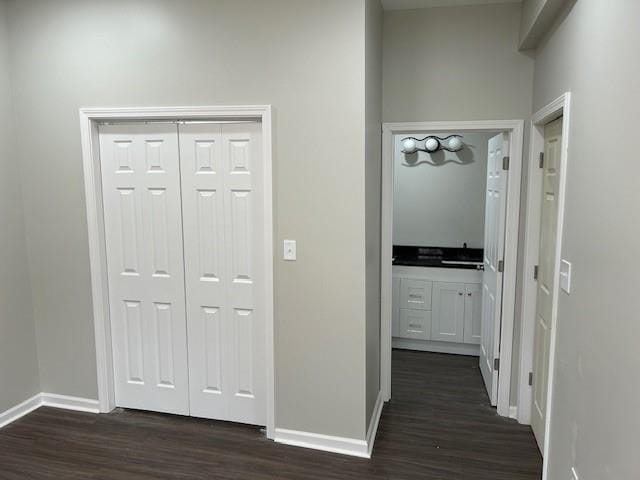 hallway featuring dark wood finished floors and baseboards