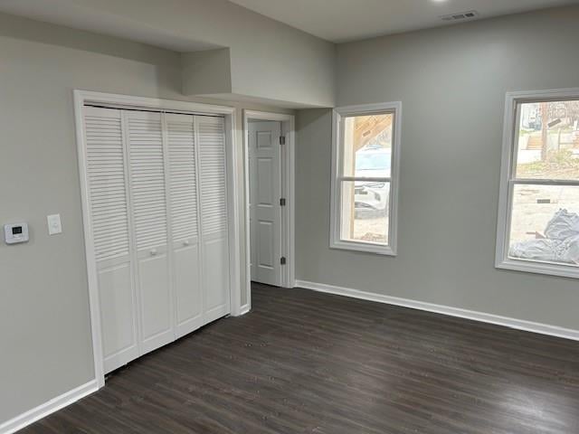 unfurnished bedroom with visible vents, baseboards, a closet, and dark wood finished floors