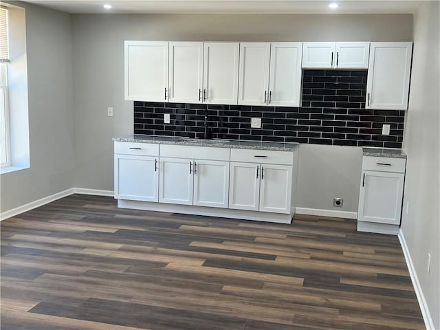 kitchen featuring dark wood-style flooring, white cabinetry, baseboards, and a sink