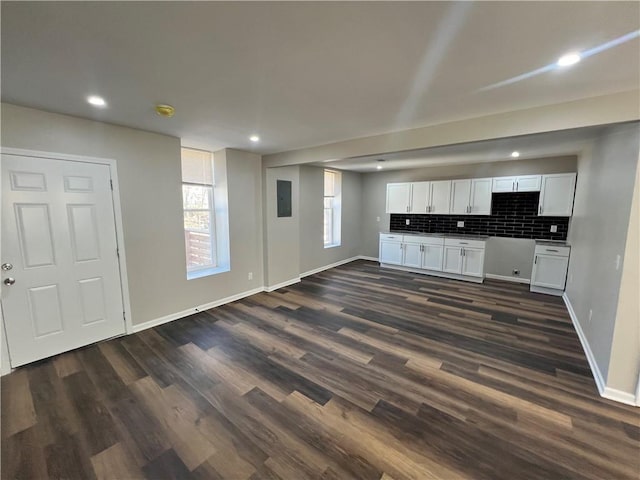 unfurnished living room featuring dark wood-style floors, electric panel, and baseboards