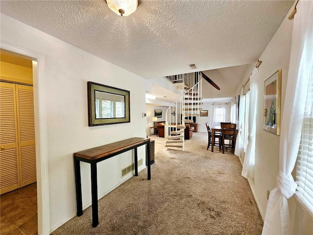 hall with visible vents, carpet, and a textured ceiling