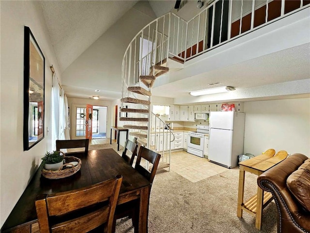 dining space with stairway, light colored carpet, and high vaulted ceiling