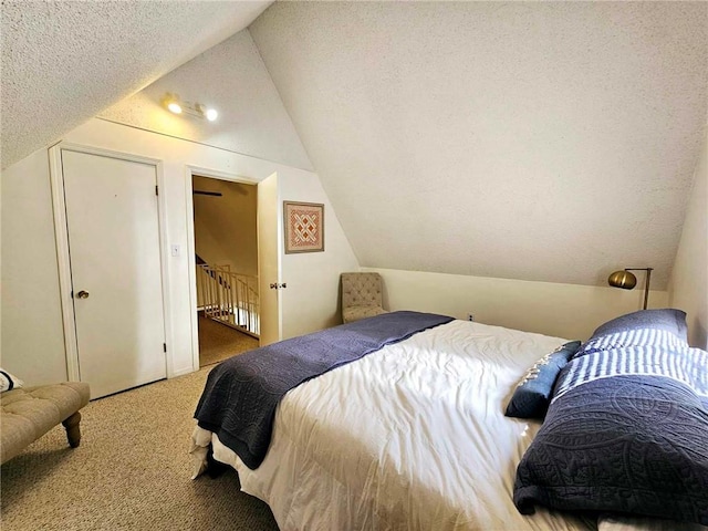 bedroom with lofted ceiling, carpet floors, and a textured ceiling