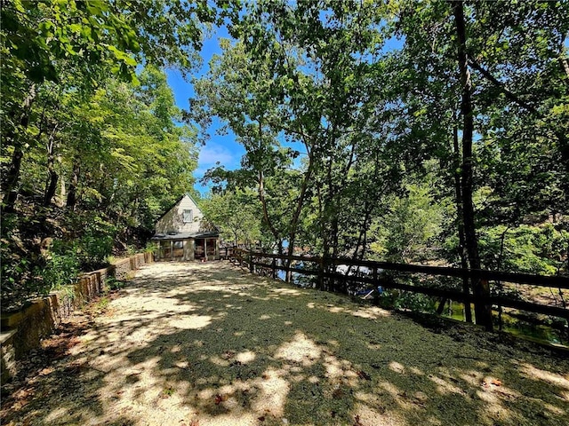 view of yard featuring a wooded view and fence