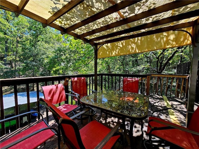 deck featuring a wooded view, a pergola, and outdoor dining area