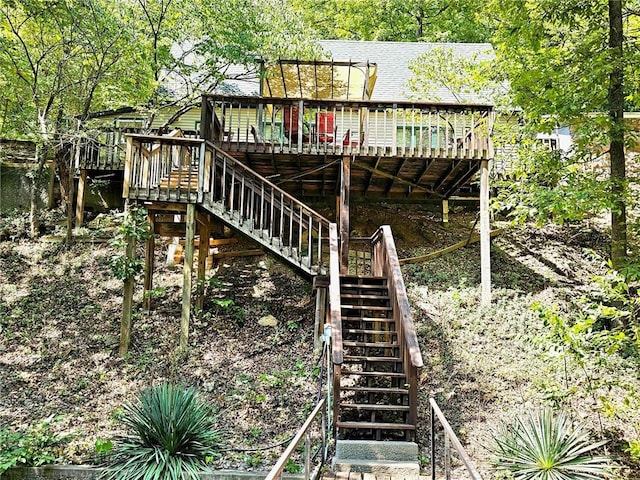 exterior space with a wooden deck, roof with shingles, and stairs