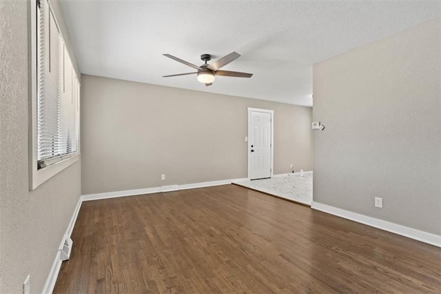 spare room featuring visible vents, a ceiling fan, a textured ceiling, wood finished floors, and baseboards