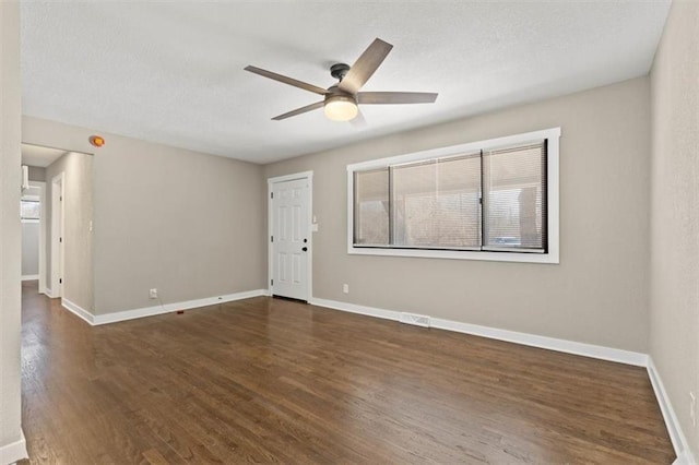 empty room with a textured ceiling, a ceiling fan, baseboards, and wood finished floors