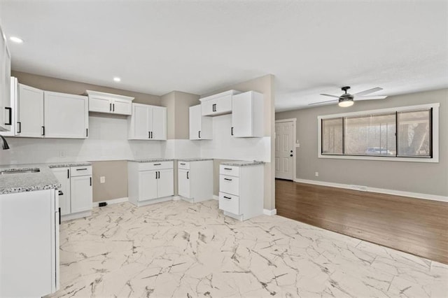 kitchen featuring a sink, baseboards, backsplash, and marble finish floor