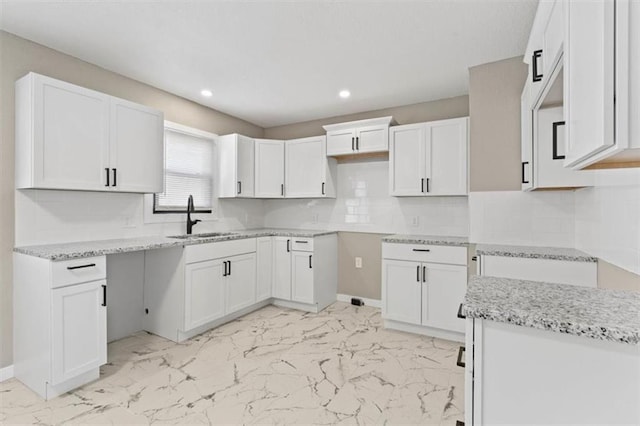 kitchen featuring marble finish floor, a sink, backsplash, recessed lighting, and light stone countertops