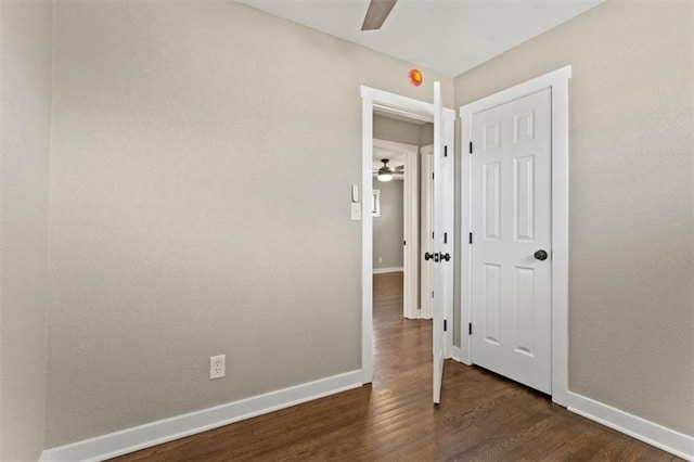 unfurnished bedroom featuring dark wood-style floors, baseboards, and ceiling fan