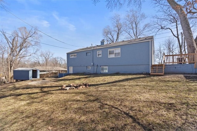 rear view of property with an outbuilding, a deck, a shed, a yard, and a chimney