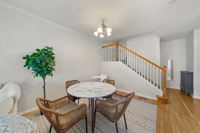 dining room with light wood-type flooring, baseboards, a chandelier, and stairs