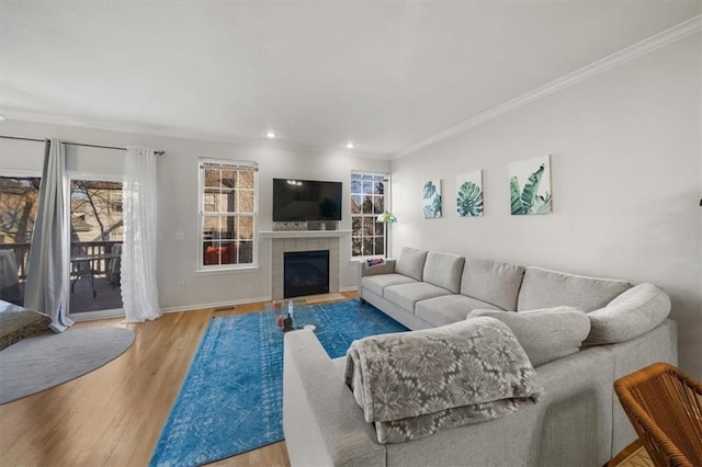 living area with crown molding, wood finished floors, baseboards, and a tile fireplace