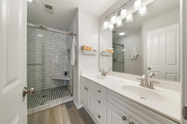 full bath with visible vents, a stall shower, wood finished floors, and a sink