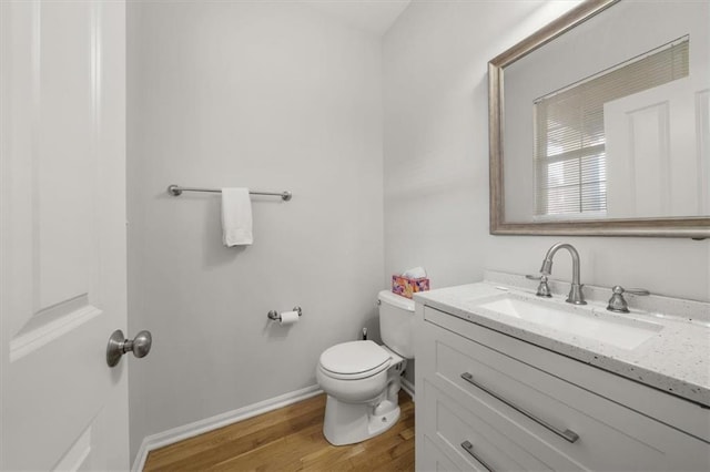 bathroom featuring toilet, vanity, baseboards, and wood finished floors