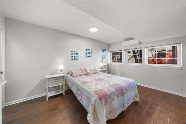 bedroom with a wall mounted air conditioner, baseboards, and wood finished floors