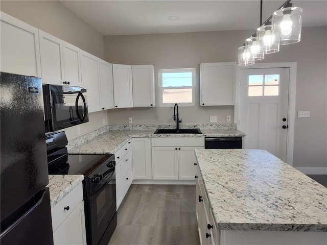 kitchen with black appliances, a kitchen island, wood finished floors, white cabinetry, and a sink