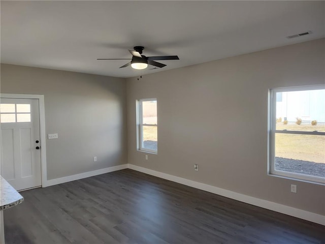 empty room with dark wood finished floors, baseboards, visible vents, and a ceiling fan