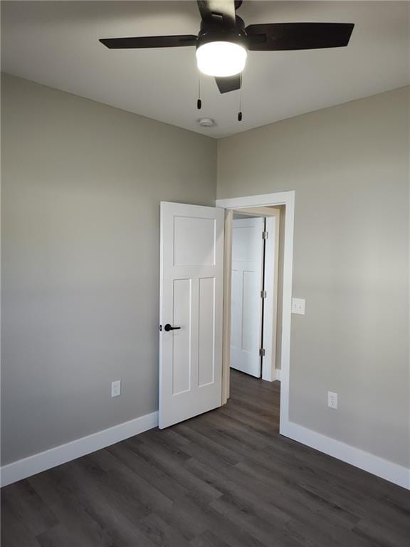 spare room featuring a ceiling fan, baseboards, and dark wood-style flooring