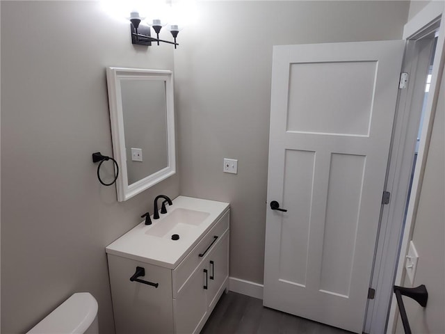 bathroom featuring toilet, vanity, baseboards, and wood finished floors