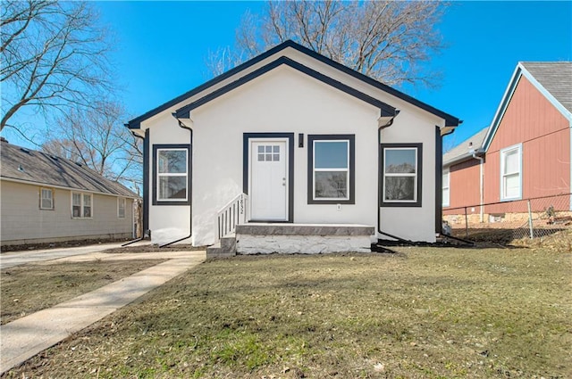 bungalow featuring stucco siding, a front lawn, and fence