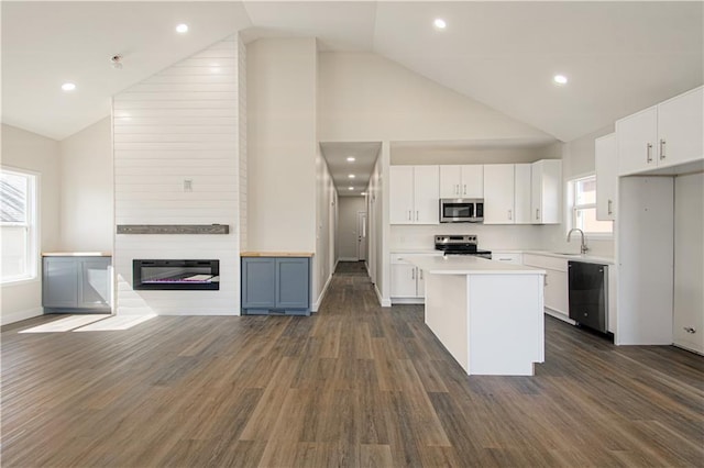 kitchen with a center island, light countertops, appliances with stainless steel finishes, white cabinets, and a sink