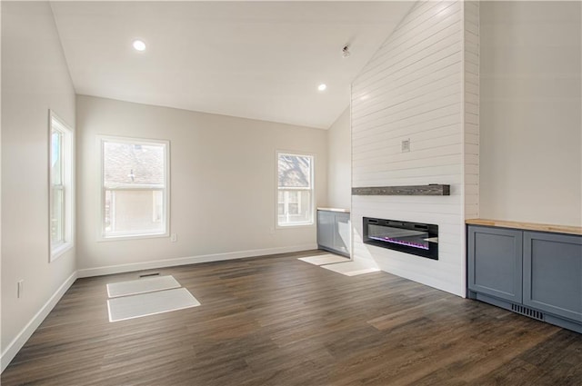 unfurnished living room with baseboards, vaulted ceiling, recessed lighting, a fireplace, and dark wood-style flooring