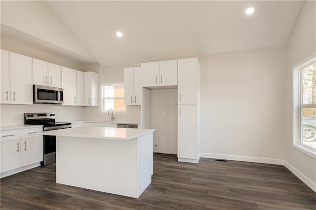 kitchen featuring vaulted ceiling, plenty of natural light, appliances with stainless steel finishes, and a center island