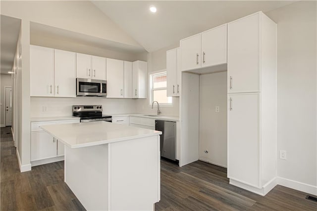 kitchen with lofted ceiling, a sink, stainless steel appliances, light countertops, and white cabinetry