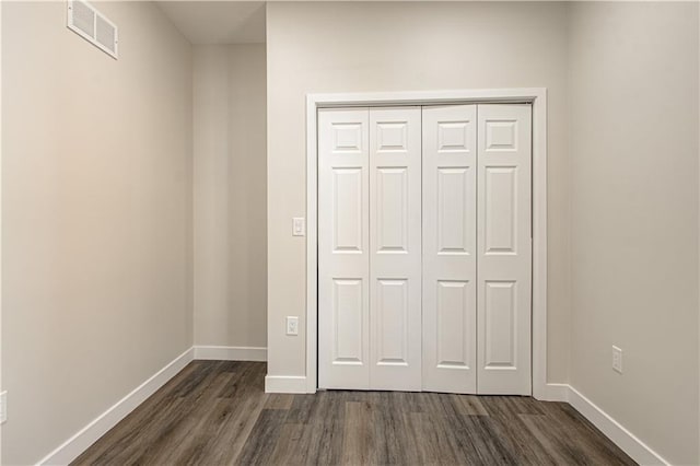 unfurnished bedroom featuring visible vents, baseboards, a closet, and dark wood-style flooring