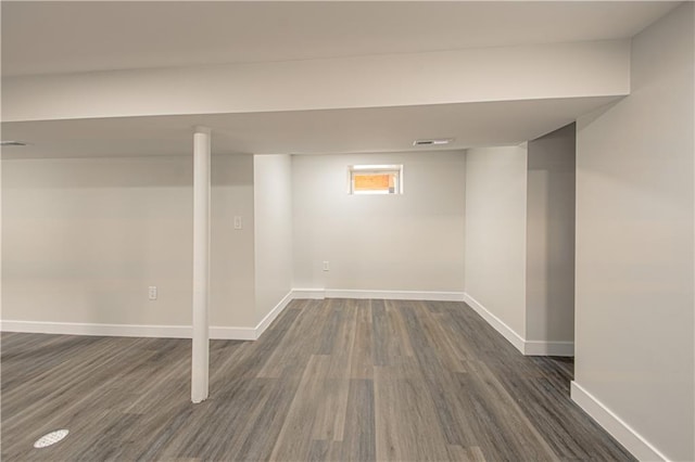 basement featuring dark wood finished floors, visible vents, and baseboards