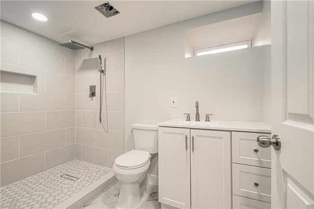 full bathroom with vanity, toilet, and a tile shower