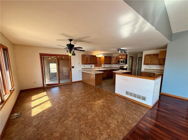 kitchen with visible vents, dark wood-type flooring, baseboards, brown cabinets, and stainless steel appliances