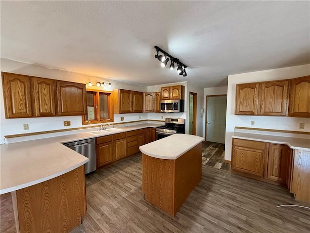 kitchen with a peninsula, dark wood-style flooring, light countertops, appliances with stainless steel finishes, and brown cabinets