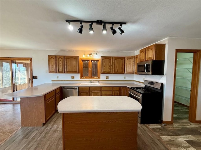 kitchen featuring a peninsula, light countertops, brown cabinets, and stainless steel appliances