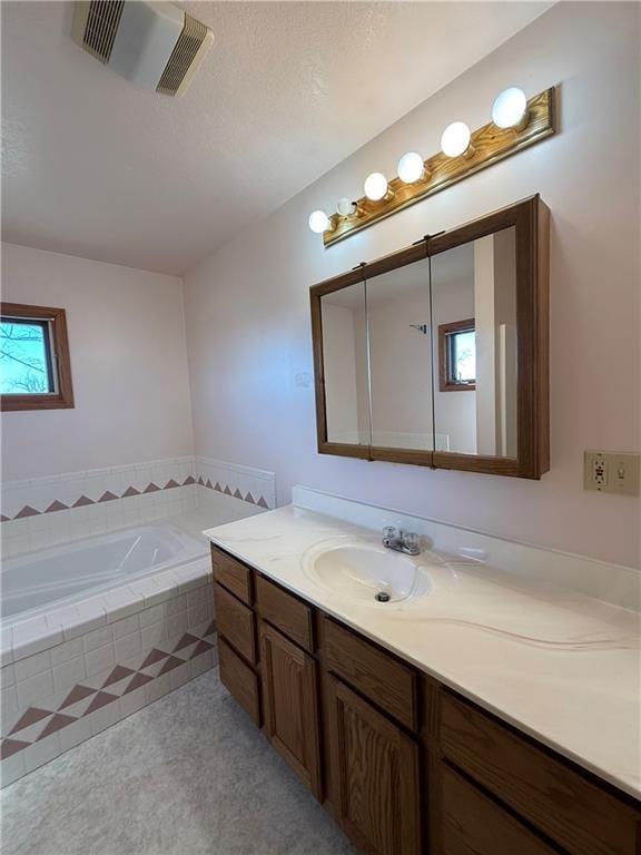 full bath featuring vanity, a bath, and visible vents