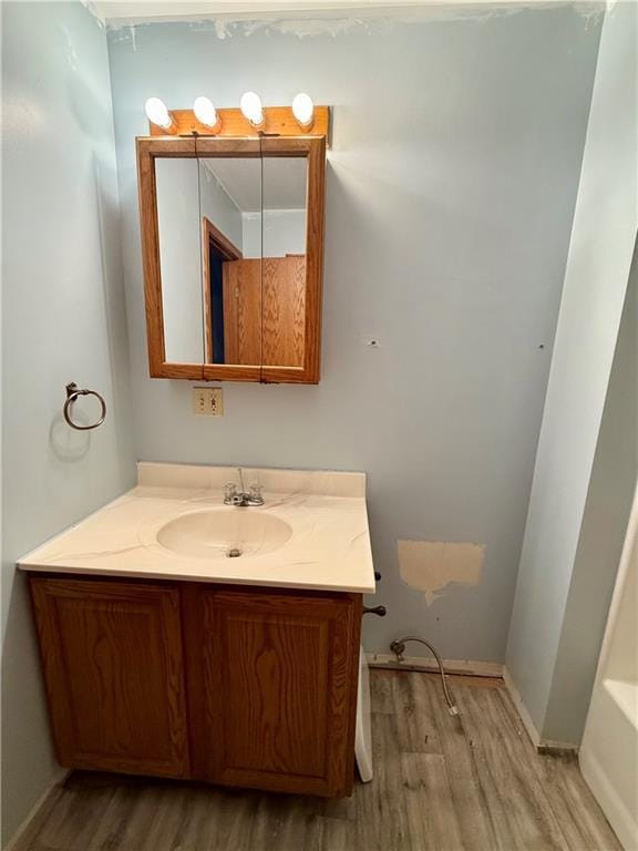 bathroom featuring a tub to relax in, wood finished floors, and vanity