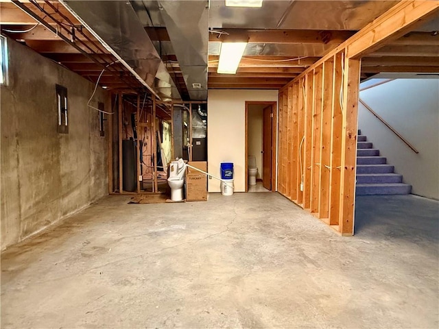 unfinished basement featuring water heater and stairway