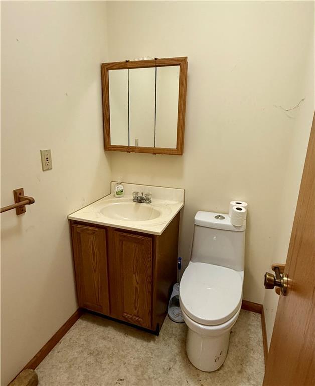 bathroom with baseboards, toilet, and vanity