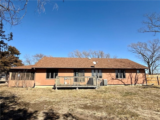 rear view of property with a wooden deck, a shingled roof, and a sunroom